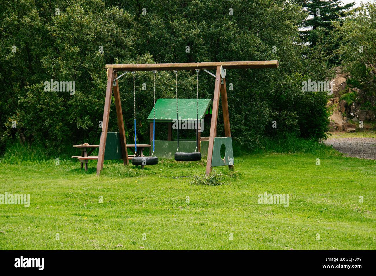 Altalene in legno e tavolo adagiati in un parco verde naturale con dintorni tranquilli. Foto Stock