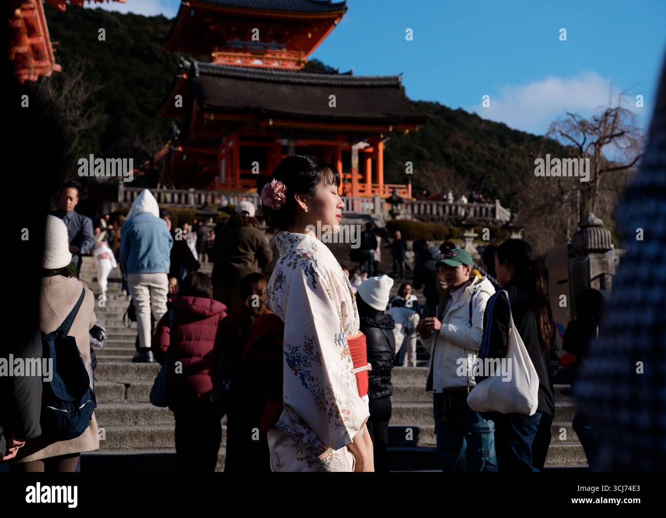 La giovane donna in kimono chiude gli occhi sotto il sole invernale a Kiyomizu-dera durante il giorno dell'età Foto Stock