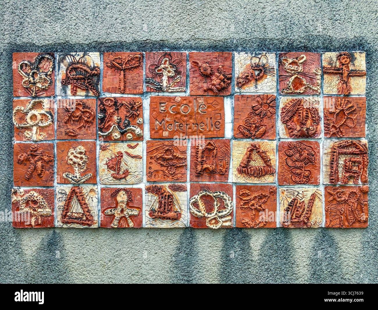 Piastrelle decorative in argilla cotte dai bambini in un pannello montato a parete da esporre presso la loro scuola - le Blanc, Indre (36), Francia. Foto Stock Piastrelle decorative in argilla cotte dai bambini in un pannello montato a parete da esporre presso la loro scuola - le Blanc, Indre (36), Francia. Foto Stock