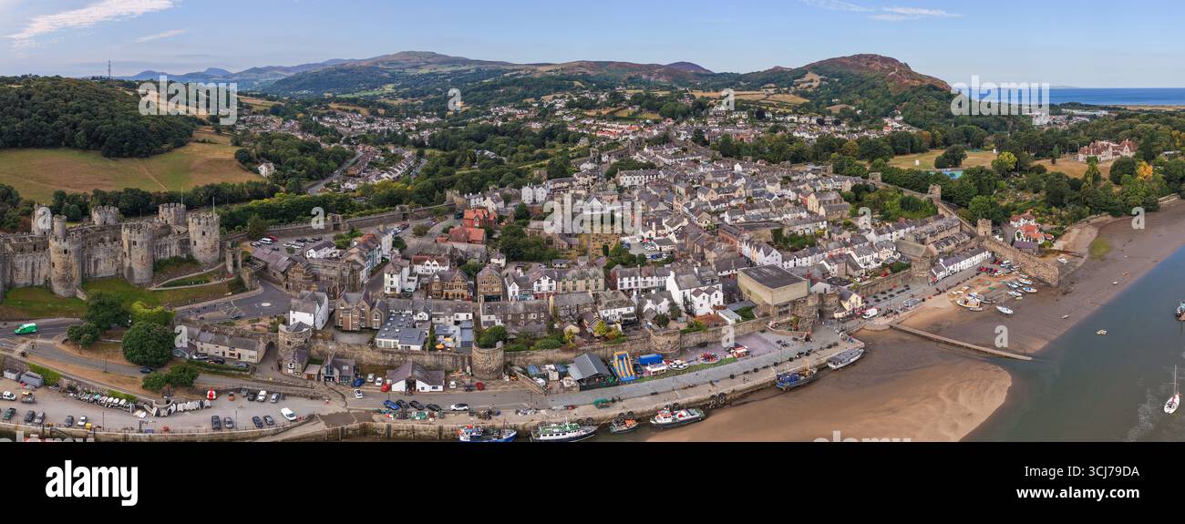 Vista aerea panoramica di Conwy, Galles, che mostra le storiche mura della città, il lungomare e la campagna circostante sotto i cieli estivi. Foto Stock