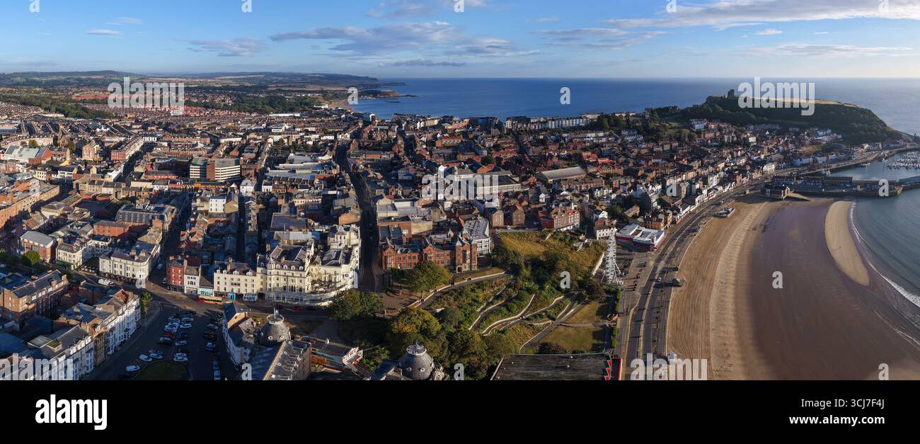 Vista aerea panoramica di Scarborough al mattino, con l'ampia spiaggia sabbiosa in primo piano, colorati edifici della città lungo il lungomare. Foto Stock
