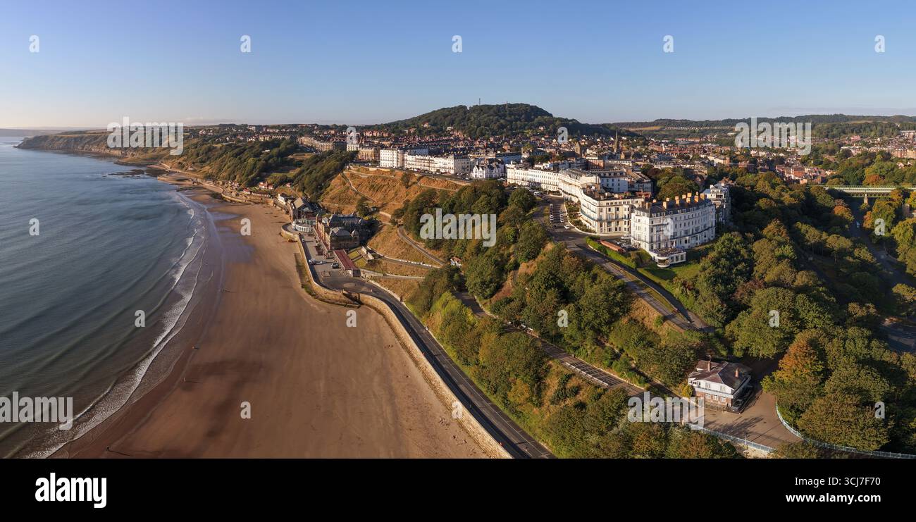 Vista panoramica aerea della costa di Scarborough al mattino, con spiagge sabbiose, scogliere, vegetazione ed eleganti edifici sul lungomare. Foto Stock