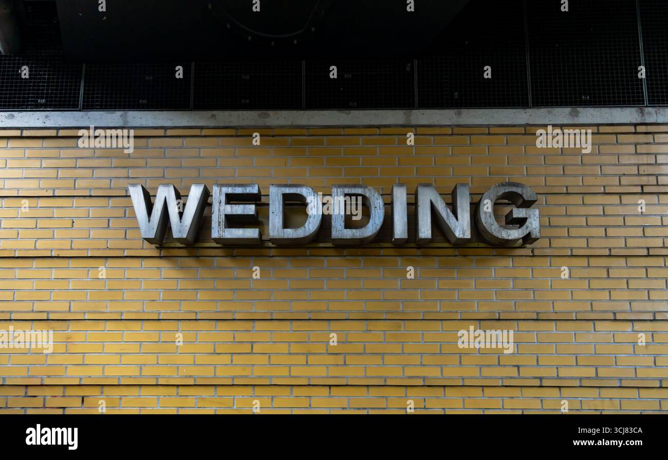 Primo piano del cartello Wedding Station sul muro di mattoni gialli nel quartiere di Berlino Wedding. Foto Stock