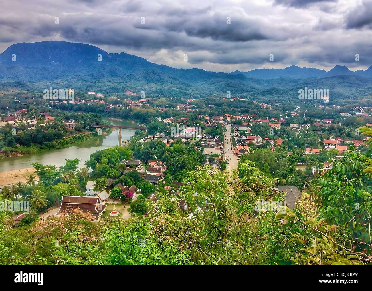 Panoramica valle fluviale a Luang Prabang, Laos, con vegetazione tropicale, tetti rossi e sfondo di montagna. Catturato il 13 ottobre 2018. Foto Stock