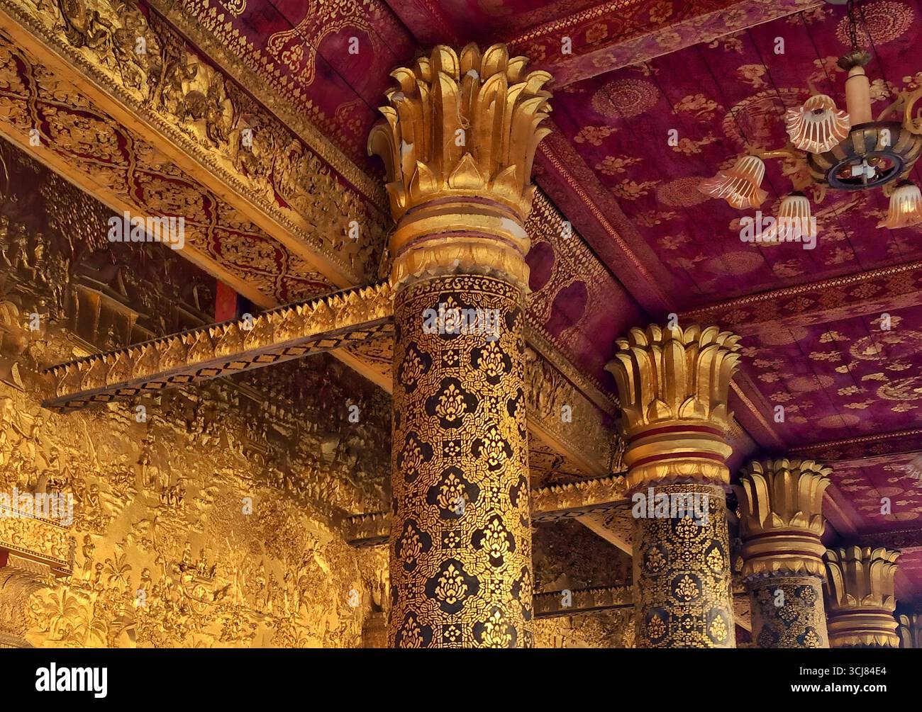 Interno del tempio tradizionale con colonne ornate, capitelli di loto d'oro e motivi rossi del soffitto. 5 ottobre 2023 Foto Stock