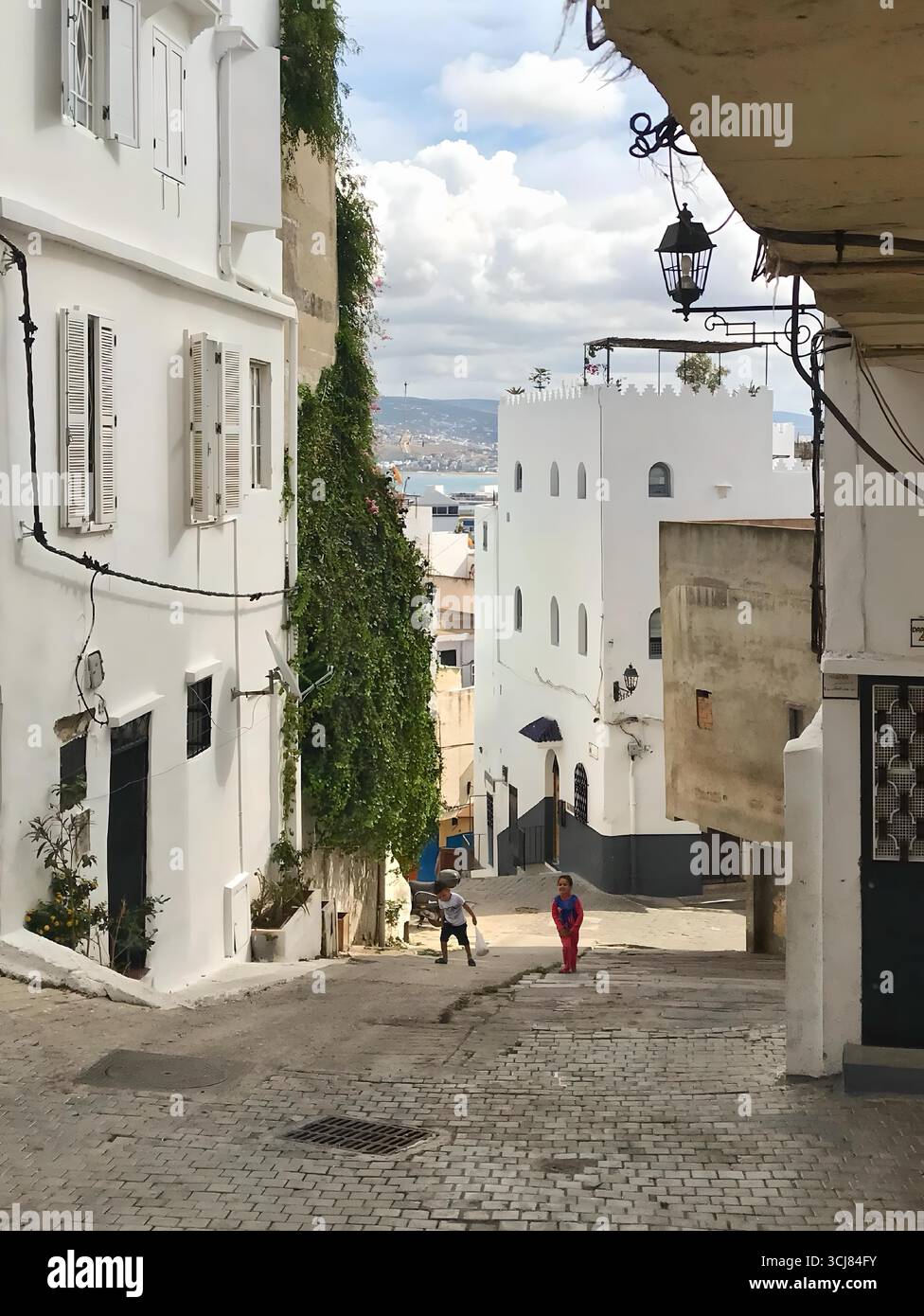 Strada inclinata con edifici imbiancati e pavimentazione in ciottoli. Vecchia Kasbah di Medina, Tangeri, Marocco 04 ottobre 2024. Foto Stock