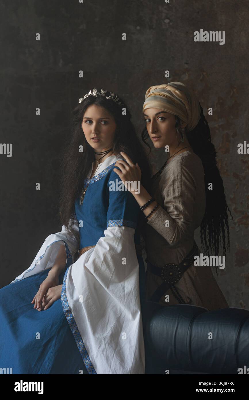 Una strega mistica zingara incanta una nobile principessa in blu, sullo sfondo di un castello medievale e in un'atmosfera fantastica. Foto Stock