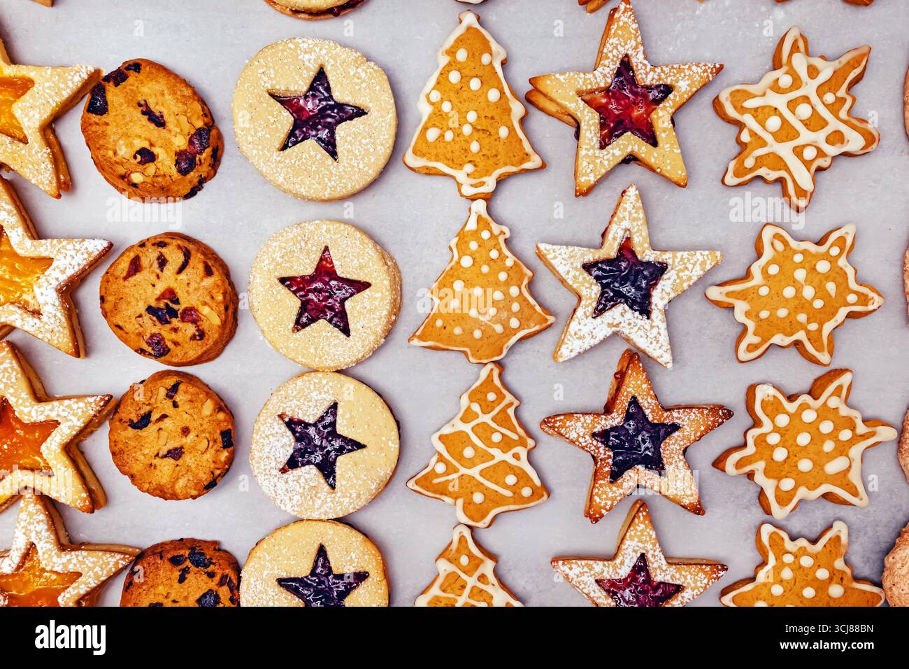 Una selezione di biscotti natalizi di varie forme come stelle, cerchi e alberi di Natale, decorati con glassa e ripieno di marmellata. Foto Stock