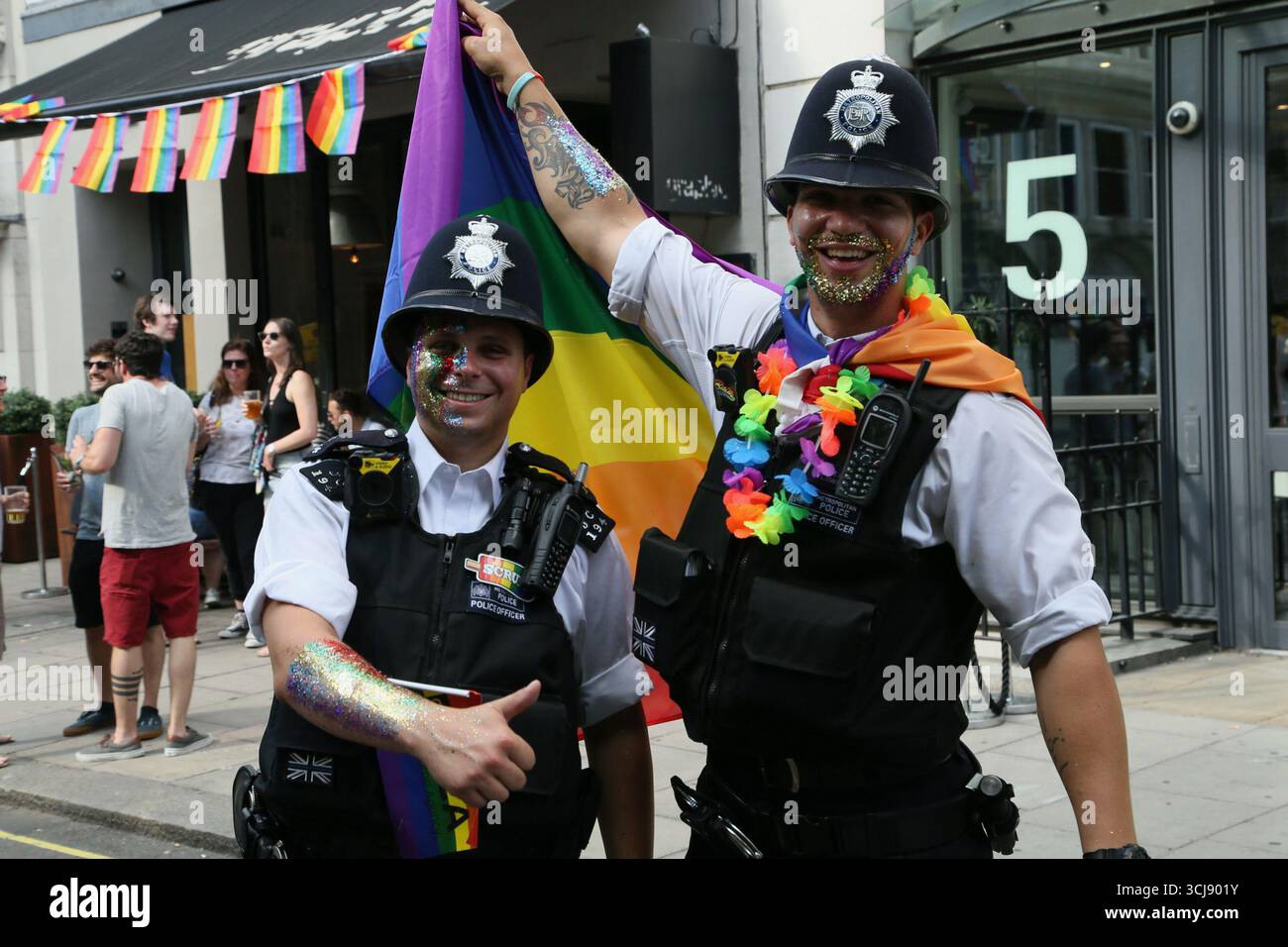 Due poliziotti britannici sorridenti che frequentano Pride a Londra in Golden Square nel 2018 Foto Stock