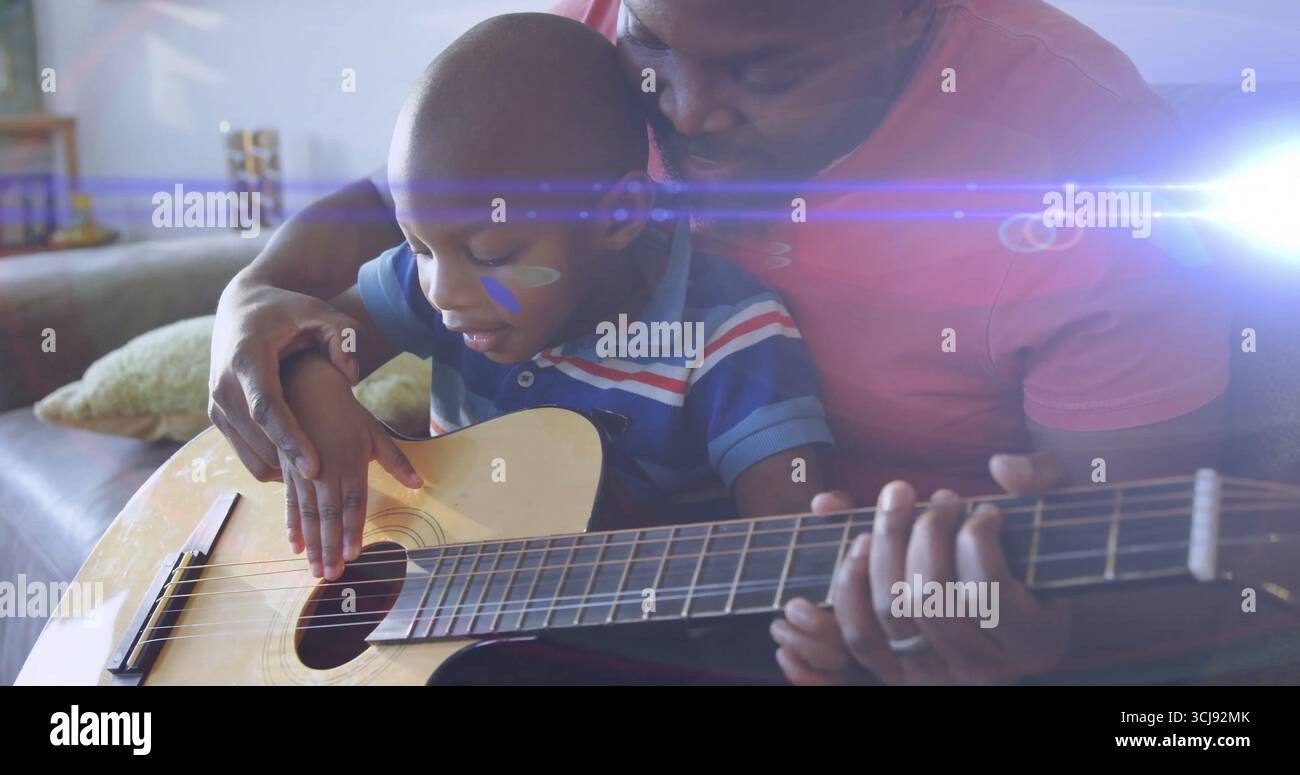 A casa, padre e figlio suonano la chitarra acustica sul divano, con cuscino decorativo e ripiano Foto Stock