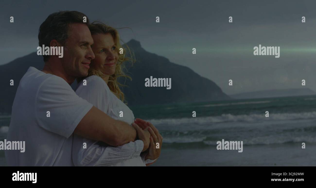 Abbracciando la coppia che guarda l'orizzonte sulla costa al crepuscolo, con un momento romantico, copia lo spazio Foto Stock