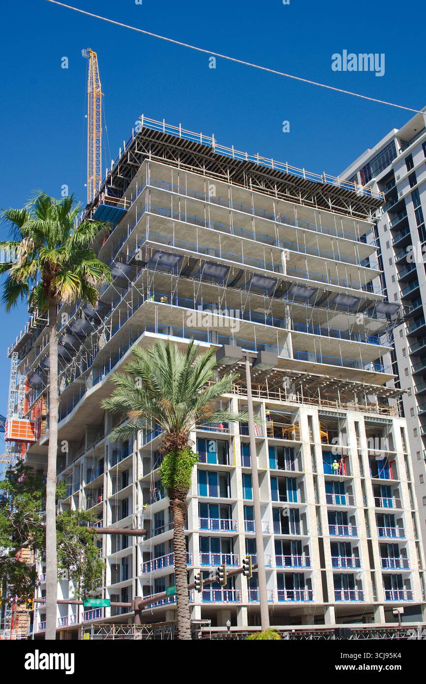 Alto edificio in costruzione con ponteggi e lavoratori. Edificio parzialmente costruito con ponteggi, lavoratori e architettura moderna Foto Stock
