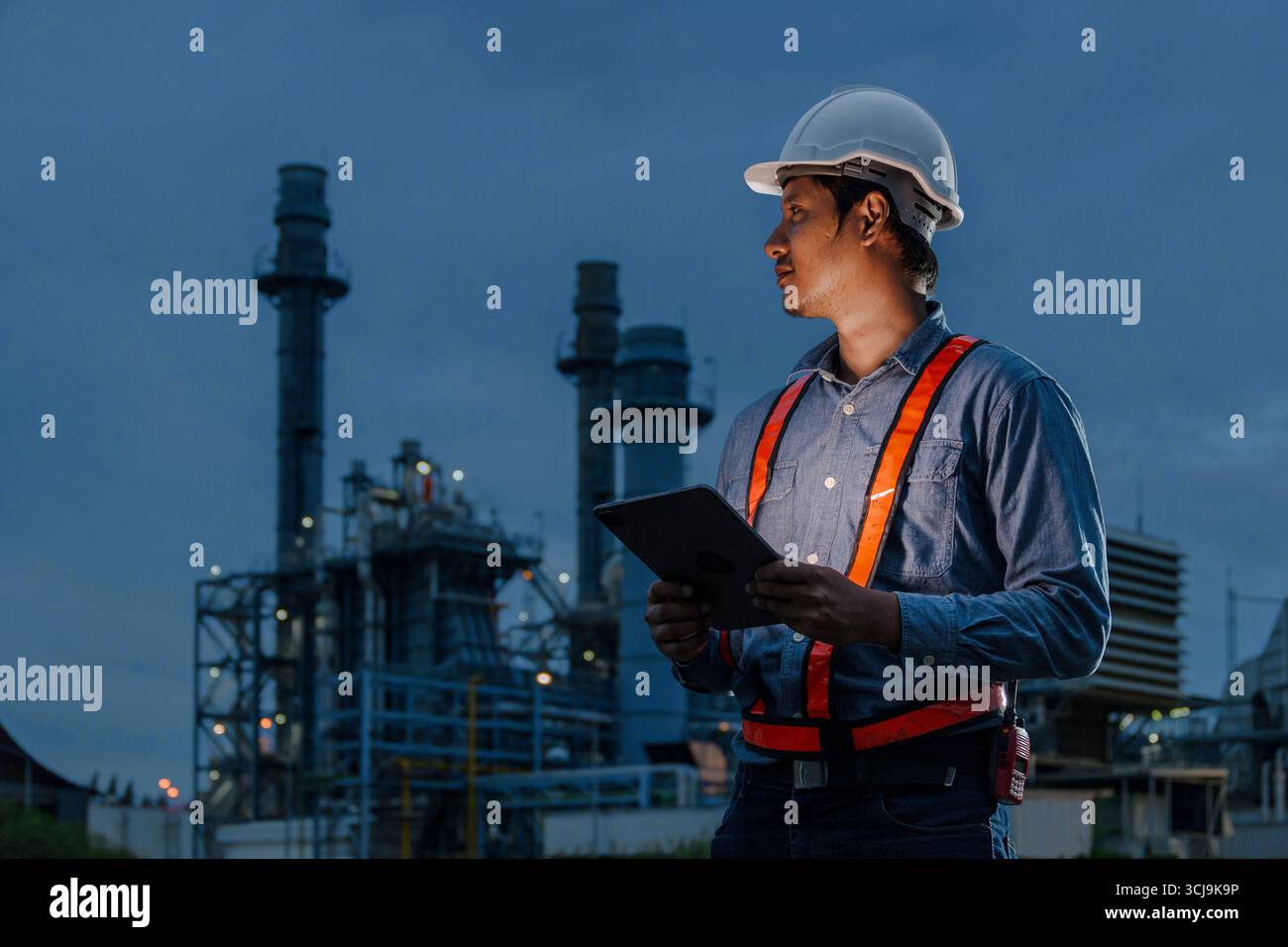 Ingegnere del turno di notte, servizio di raffineria di petrolio e gas, lavoratore di sesso maschile, duro lavoro negli impianti dell'industria petrolifera, sfondo scuro. Foto Stock