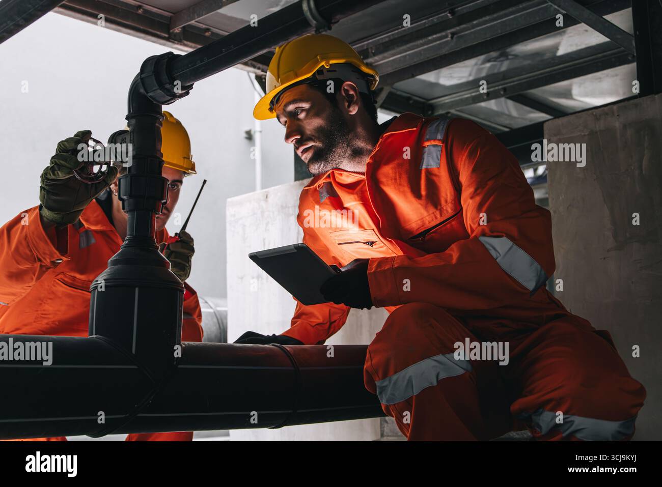 Due ingegneri professionisti maschio di servizio di squadra manutenzione, sistema di valvole per tubi dell'acqua per l'industria dei lavoratori Foto Stock