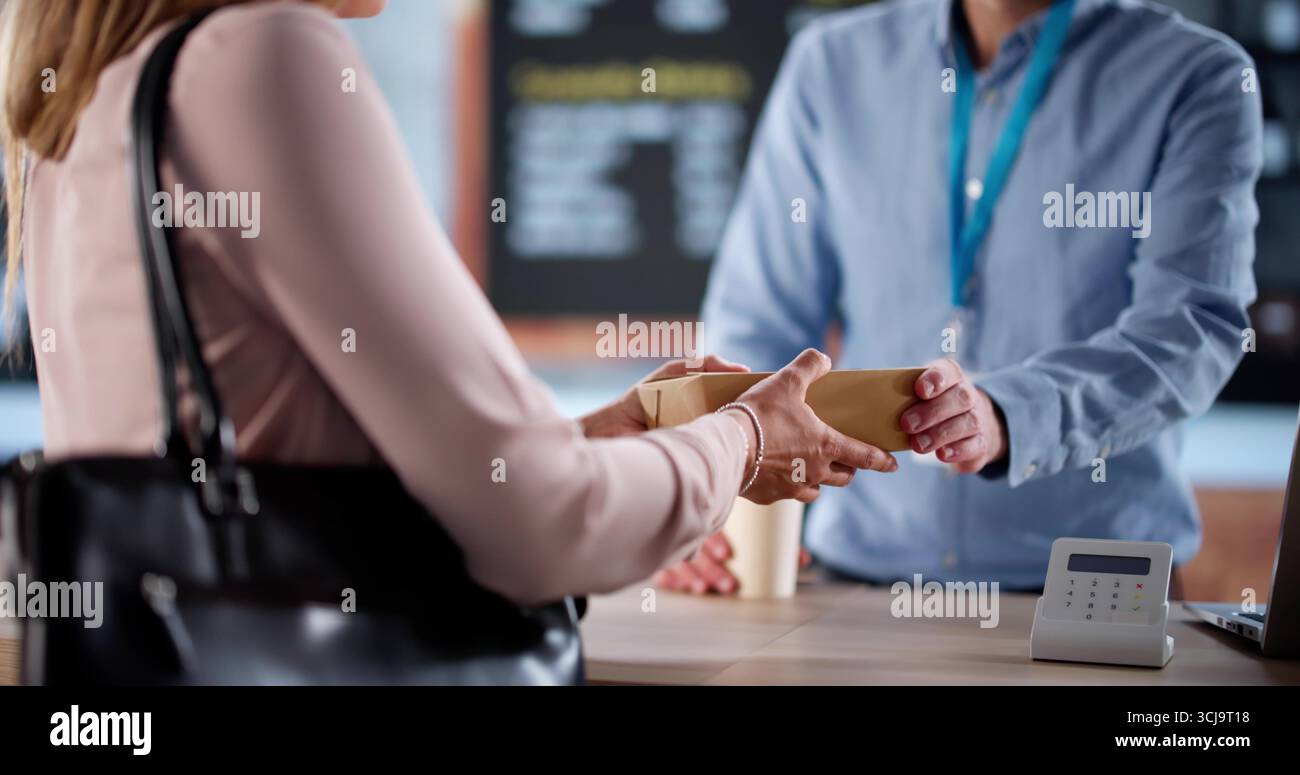 Una donna d'affari affollata ordina un espresso mattutino dal proprietario di una caffetteria locale Foto Stock