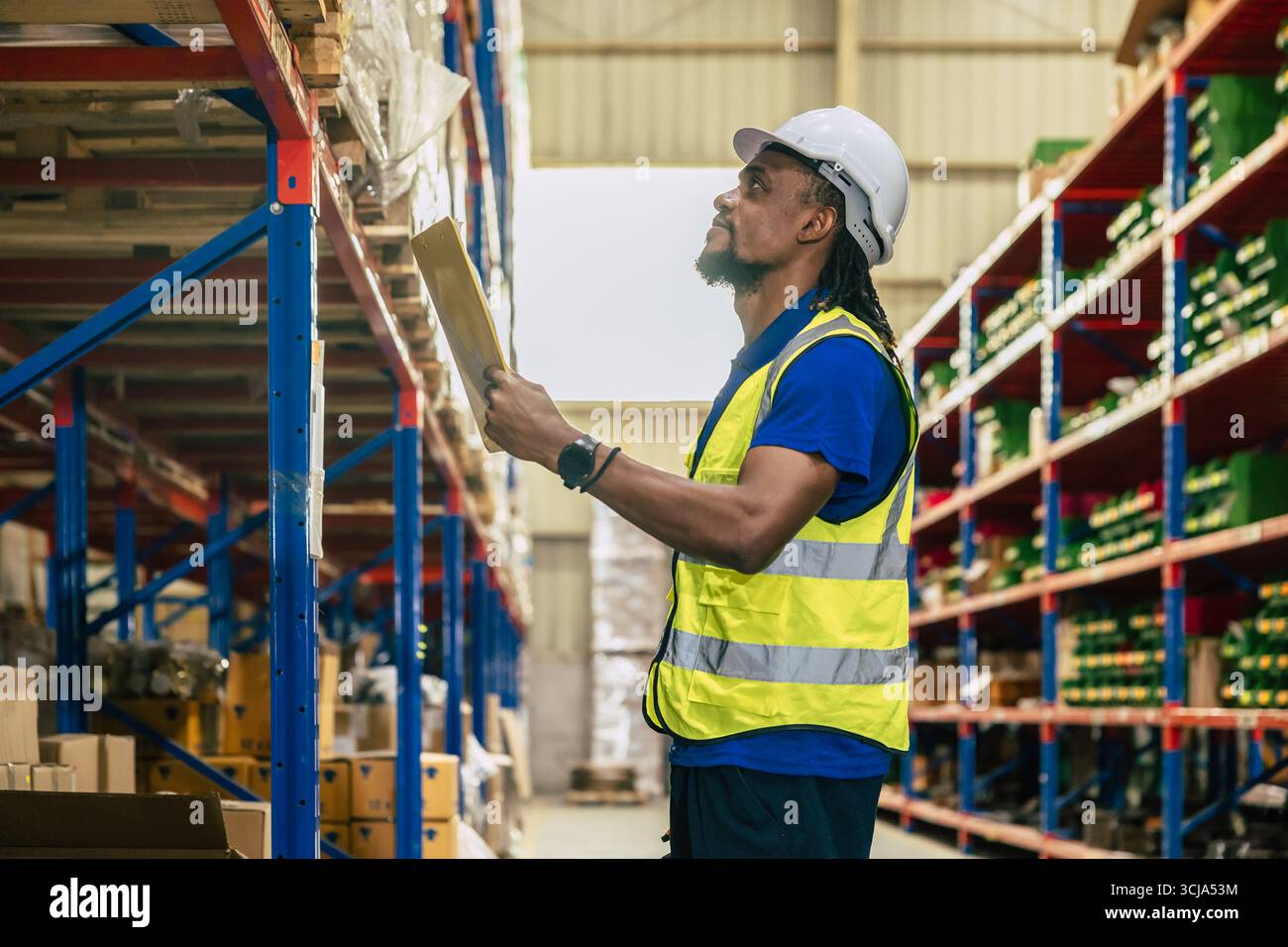 il lavoratore del personale di magazzino lavora nel magazzino merci per il settore logistico della fornitura di prodotti di spedizione, alla ricerca di un pacco sullo scaffale Foto Stock