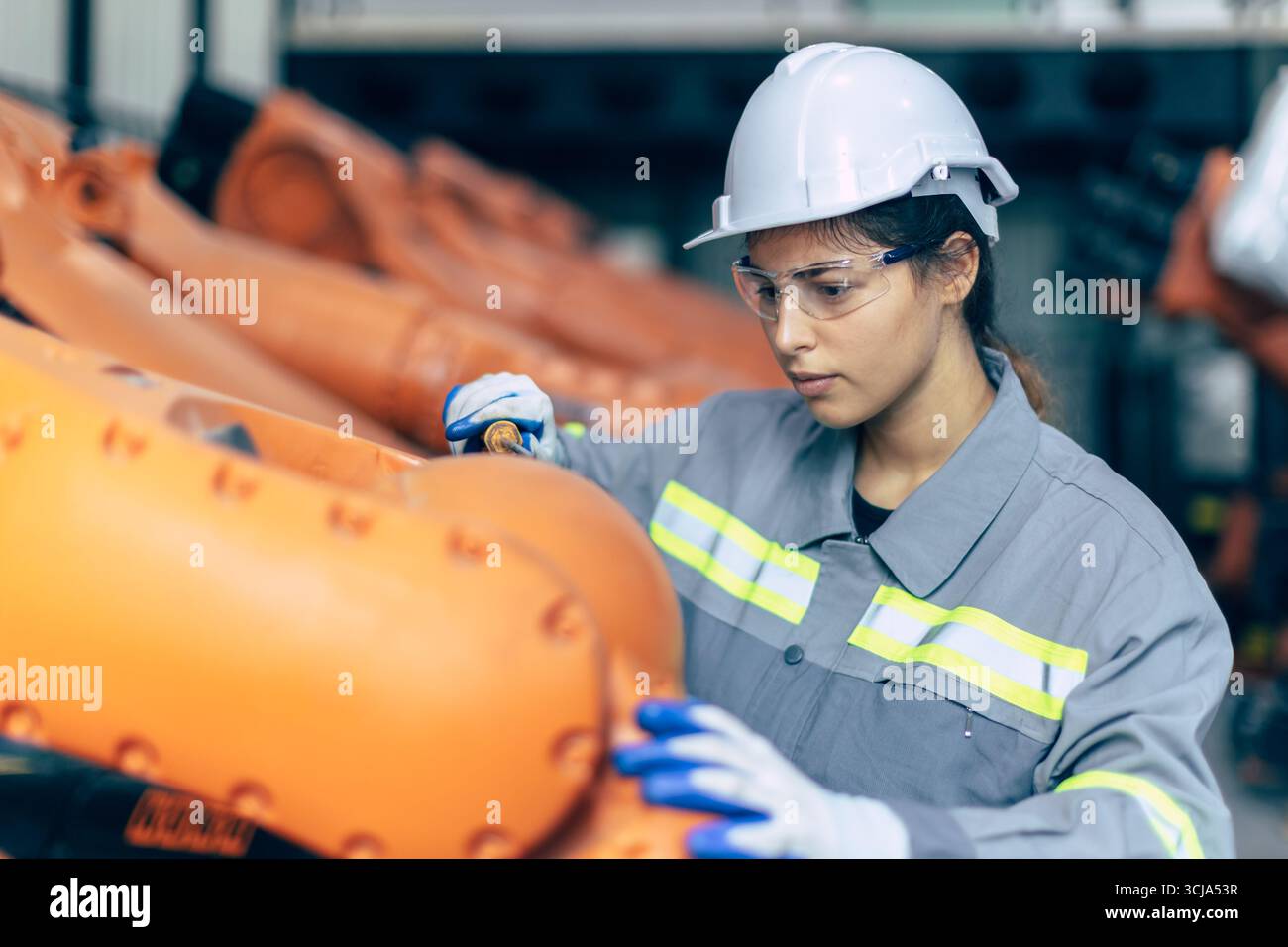 Ingegnere donna che lavora in fabbrica di macchine. Il personale di ingegneria femminile indiana lavora controllando il braccio robot nell'impianto di assemblaggio Foto Stock