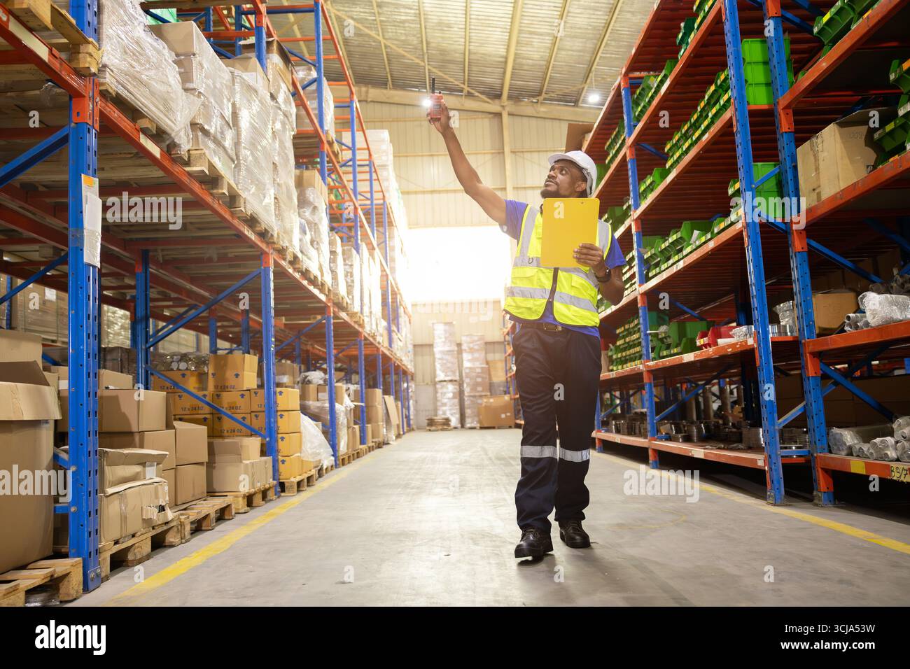 il lavoratore del personale di magazzino lavora nel magazzino merci per il settore logistico della fornitura di prodotti di spedizione, alla ricerca di un pacco sullo scaffale Foto Stock