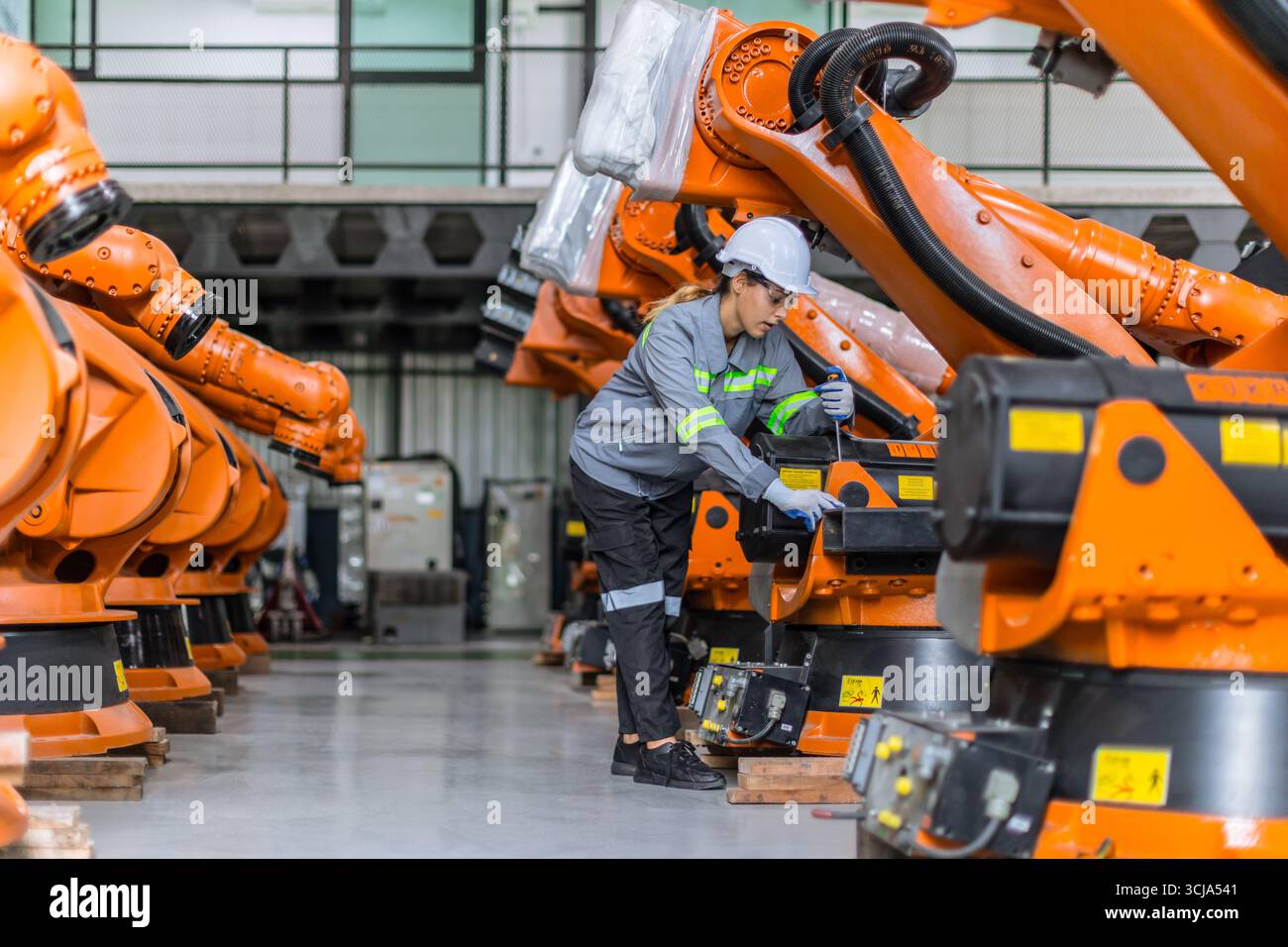 Ingegnere donna che lavora in fabbrica di macchine. Il personale di ingegneria femminile indiana lavora controllando il braccio robot nell'impianto di assemblaggio Foto Stock