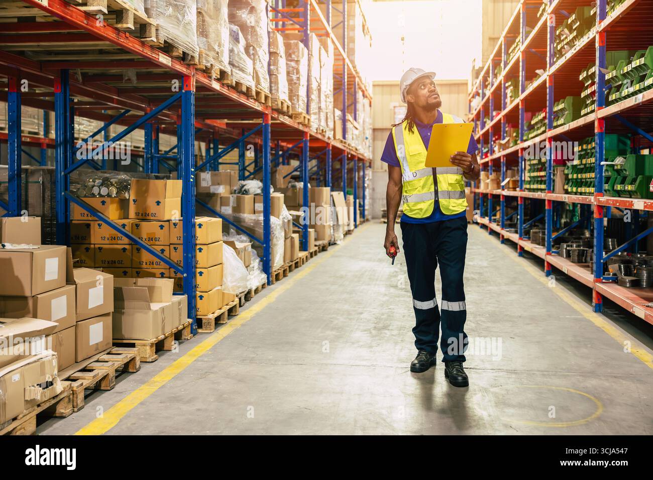 il lavoratore del personale di magazzino lavora nel magazzino merci per il settore logistico della fornitura di prodotti di spedizione, alla ricerca di un pacco sullo scaffale Foto Stock