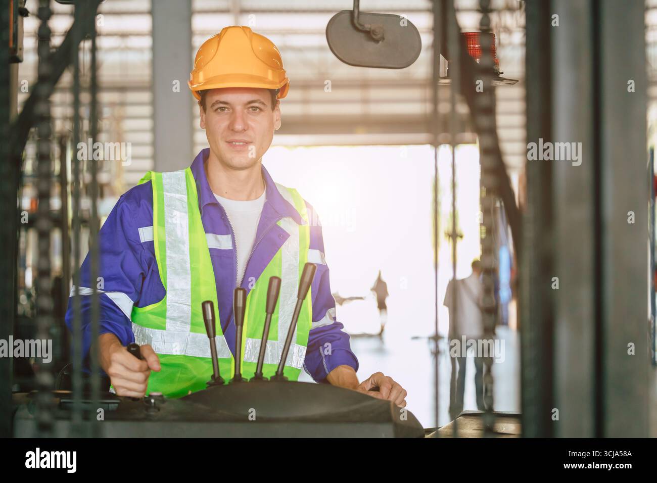 felice e sorridente camionista di carrelli elevatori. lavoratore professionista di stoccaggio del carico in fabbrica. personale addetto all'inventario delle scorte nel settore della logistica dei prodotti Foto Stock