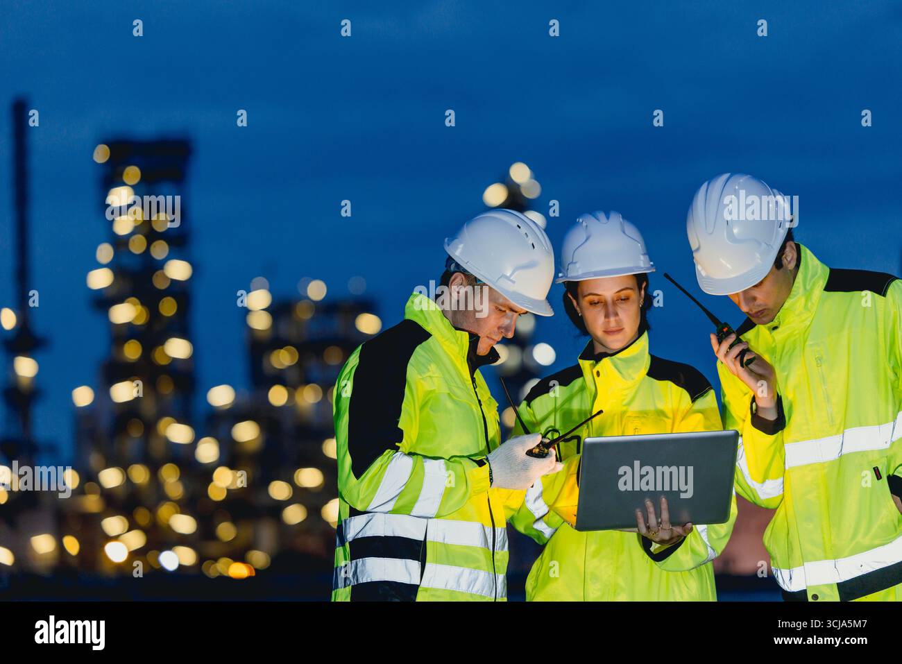 Gruppo di ingegneri che lavorano a turno notturno per il servizio di raffineria di petrolio e gas, lavoratori che lavorano sodo negli stabilimenti notturni dell'industria petrolifera. Foto Stock