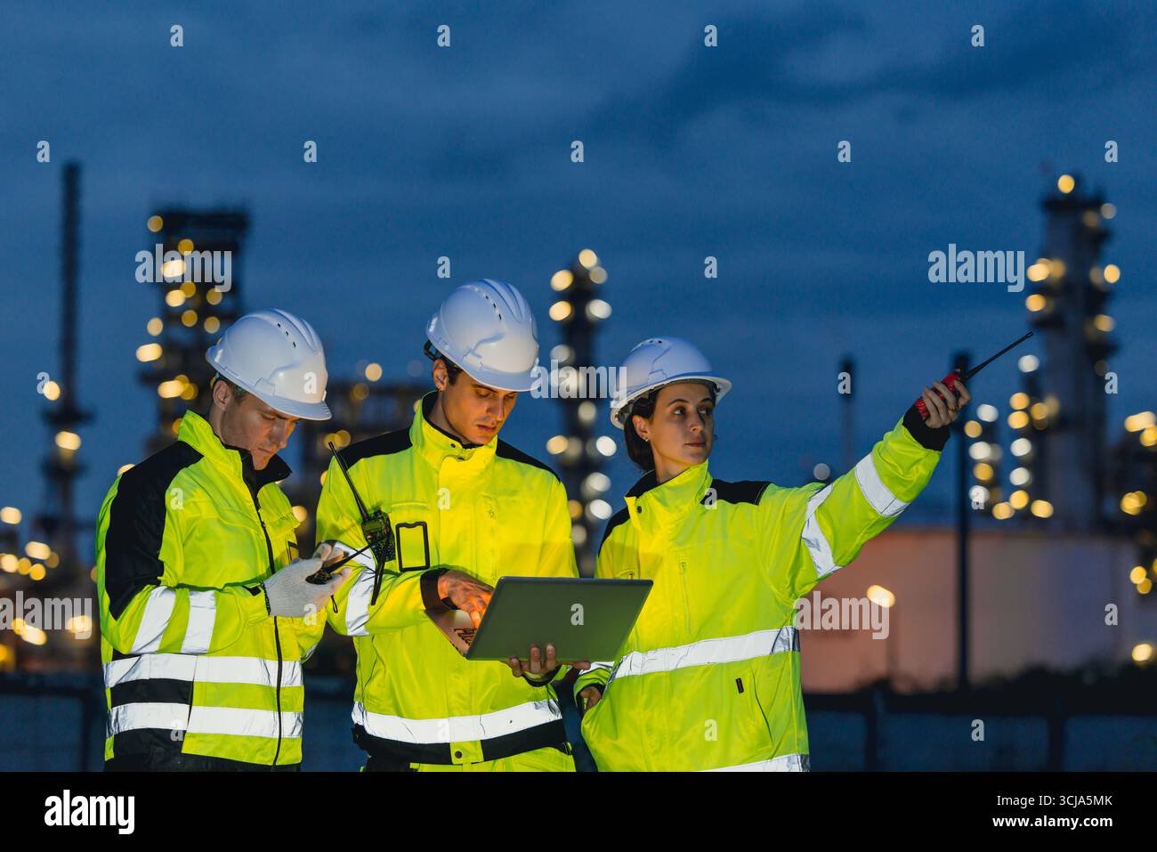 Gruppo di ingegneri che lavorano a turno notturno per il servizio di raffineria di petrolio e gas, lavoratori che lavorano sodo negli stabilimenti notturni dell'industria petrolifera. Foto Stock