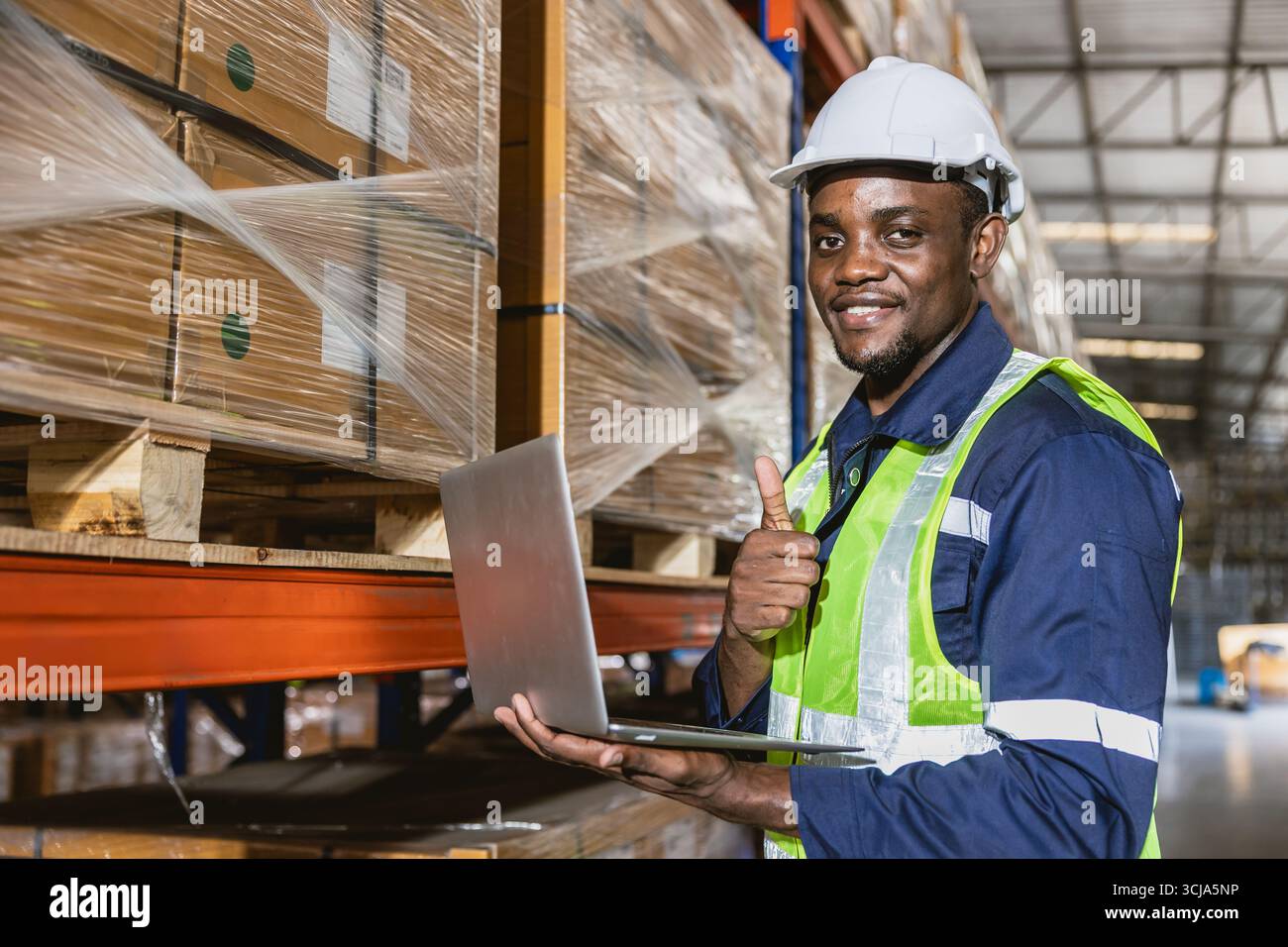 ritrattista professionista nero africano del magazzino. il personale dell'inventario delle scorte è soddisfatto dell'utilizzo di un computer portatile per assistere la gestione delle scorte Foto Stock