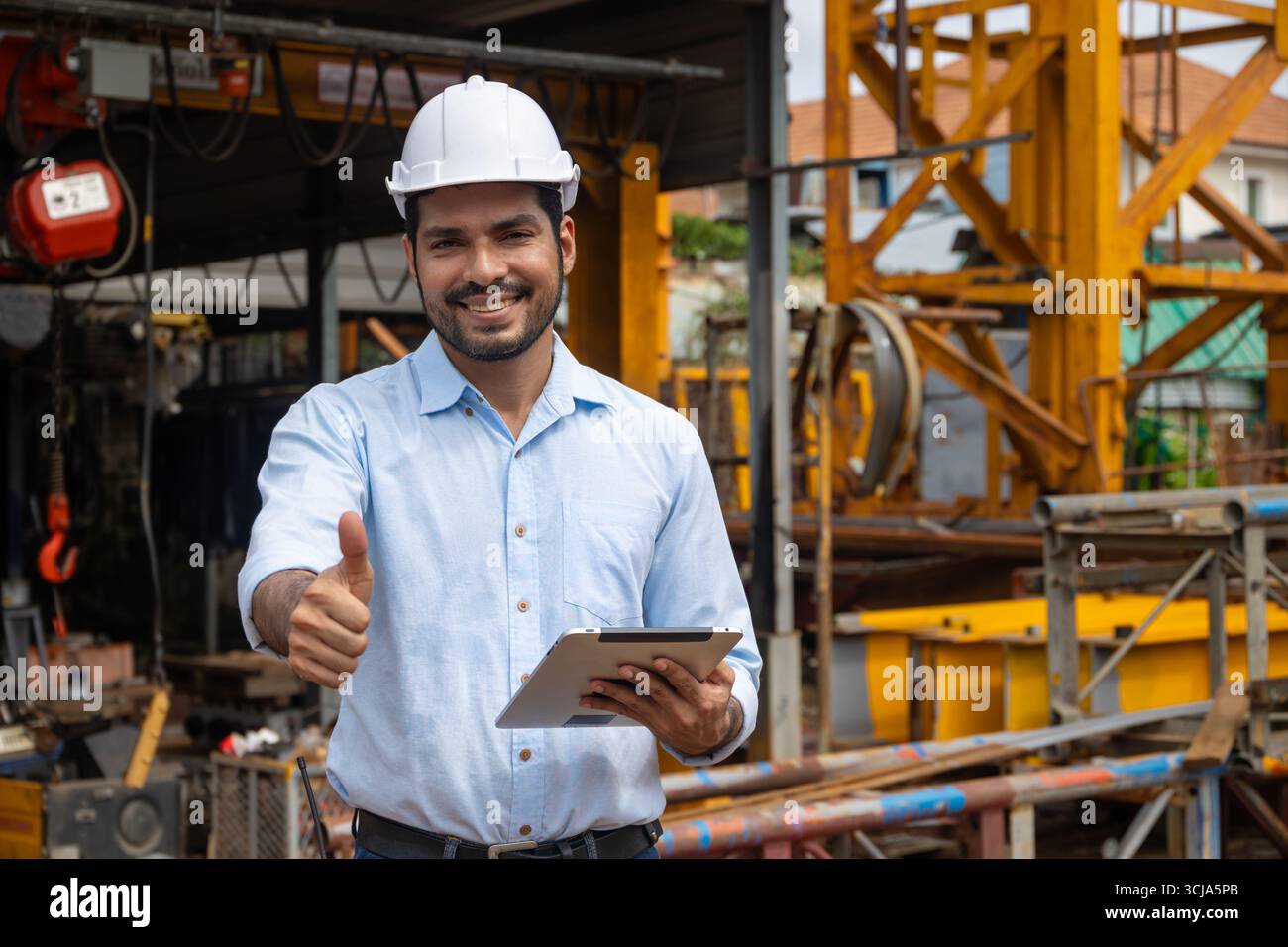 Ritratto ingegnere edile ispanico indiano lavoratore maschile nel cantiere con elmetto di sicurezza e tablet computer sorridente pollice in alto Foto Stock