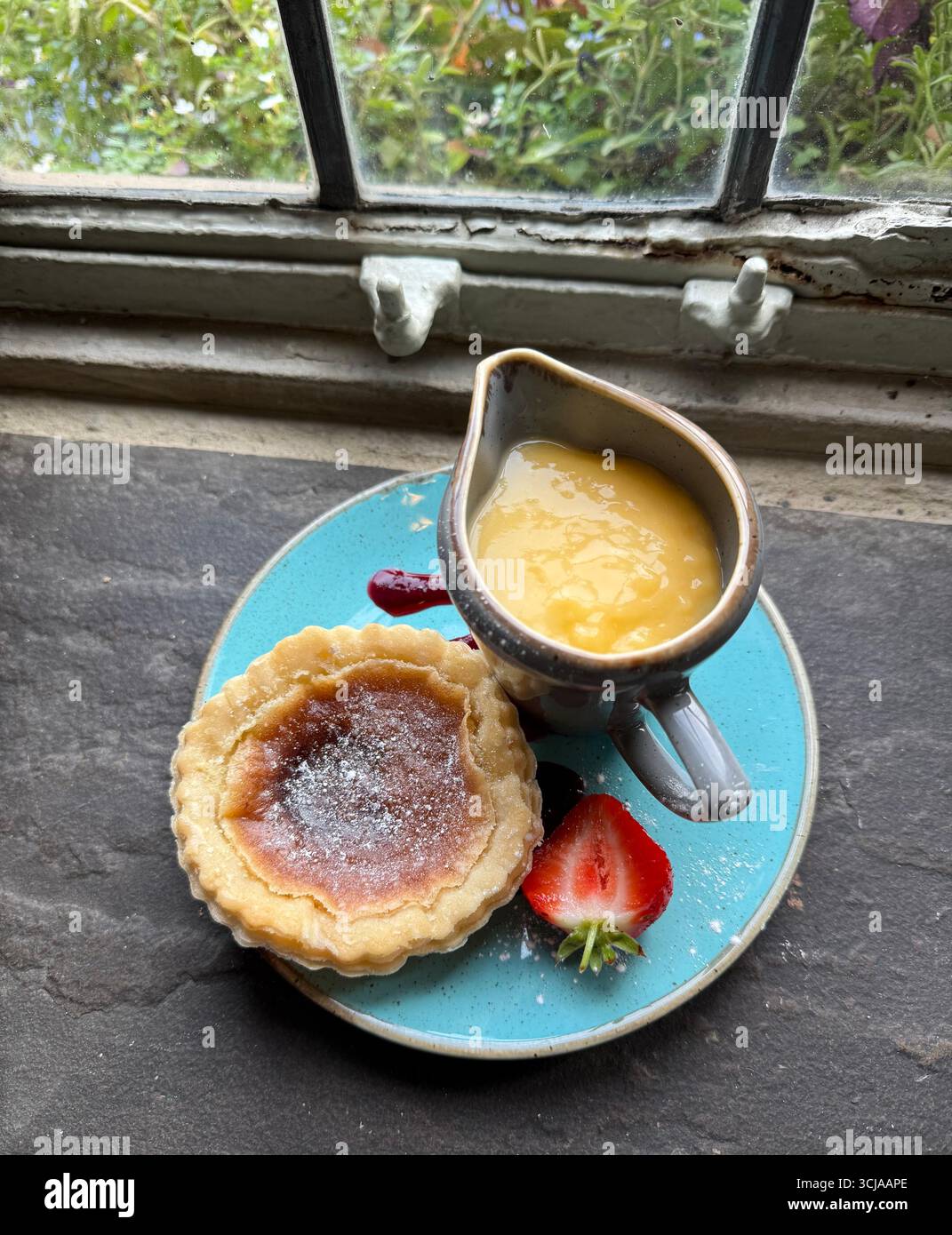 Bakewell Pudding e una brocca di crema pasticcera - Immagine stock catturata con smartphone