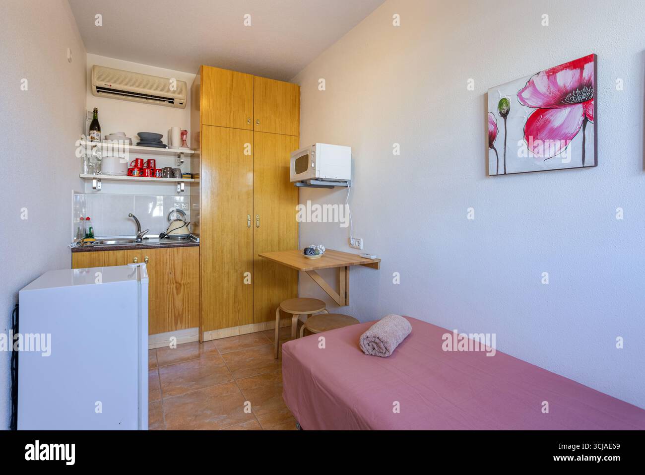 Monolocale compatto con cucinotto, armadi in legno e piccola zona pranzo. Foto Stock