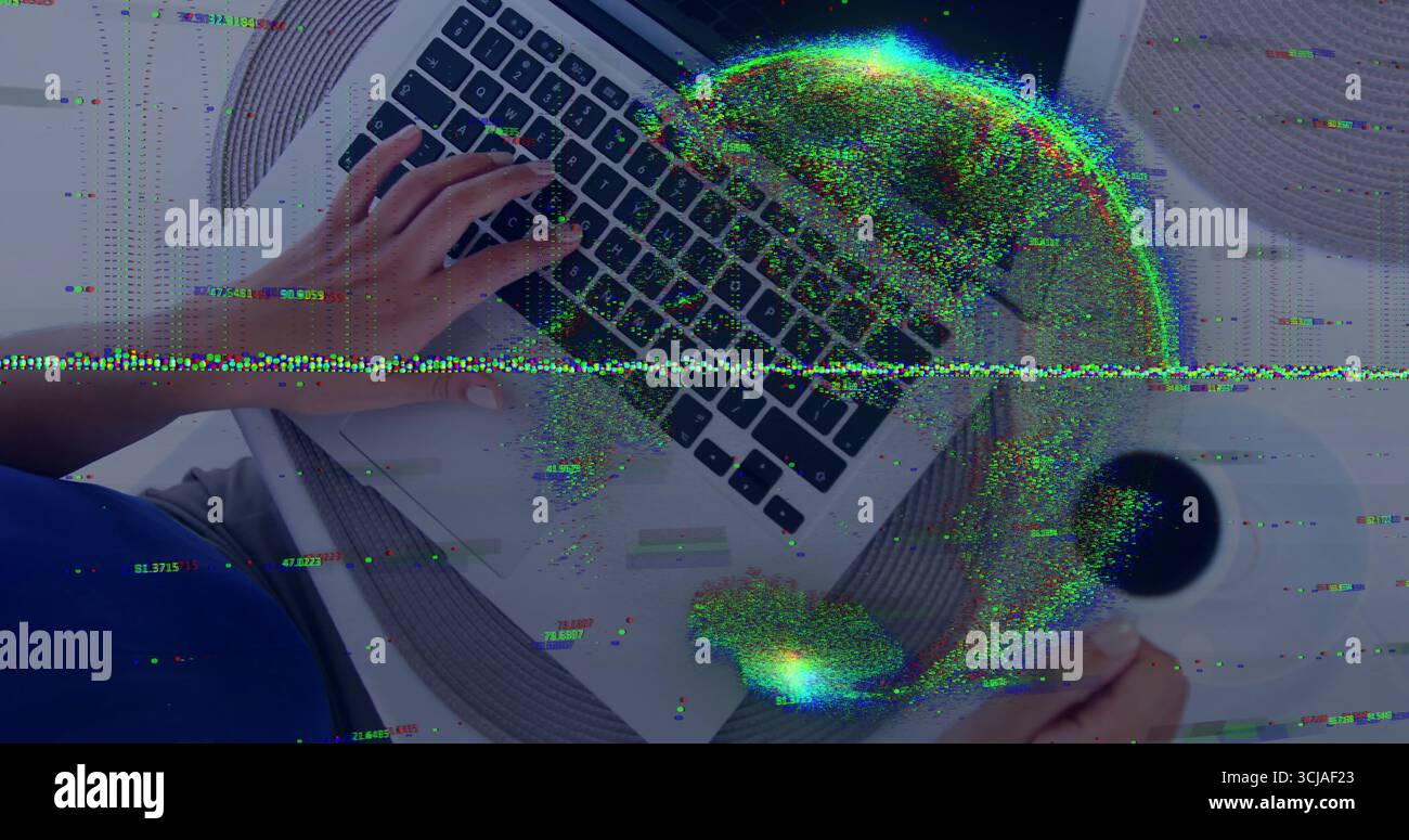 Donna ispanica che scrive su un computer portatile tenendo la tazza del caffè in casa con tovaglietta e globo dati Foto Stock
