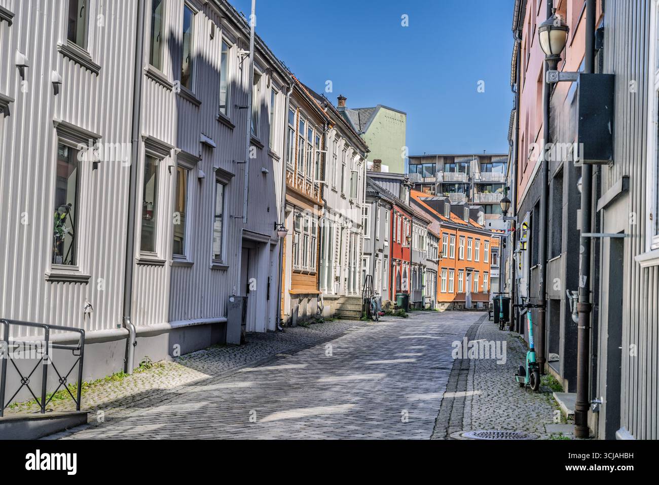 Strada pittoresca con vecchie case vibranti, pavimentazione di ciottoli e cielo azzurro, che mostra un'architettura serena e un'affascinante atmosfera urbana, pe Foto Stock