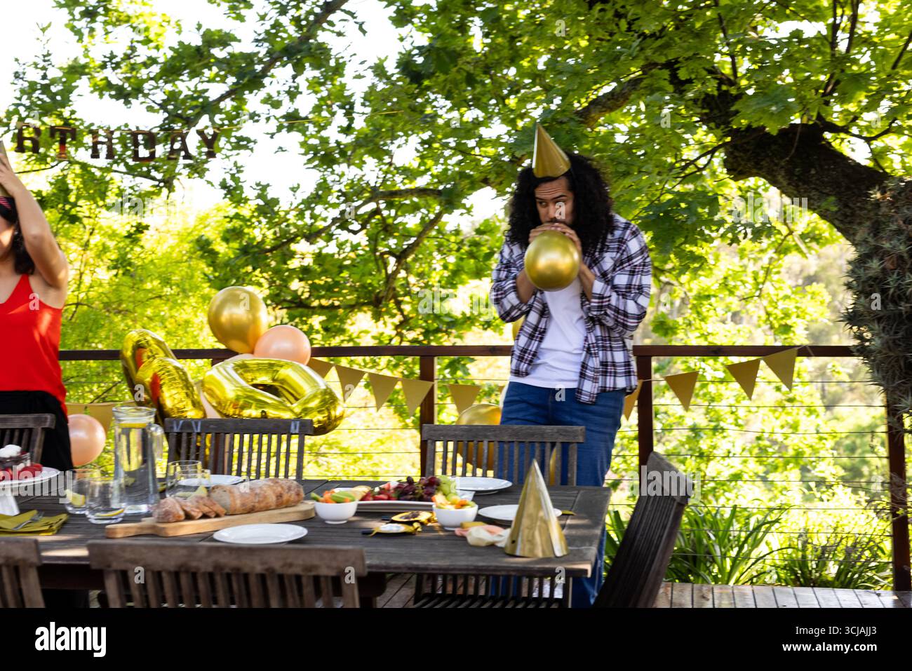 Uomo che gonfia la mongolfiera alla festa all'aperto con decorazioni e cibo festivi Foto Stock