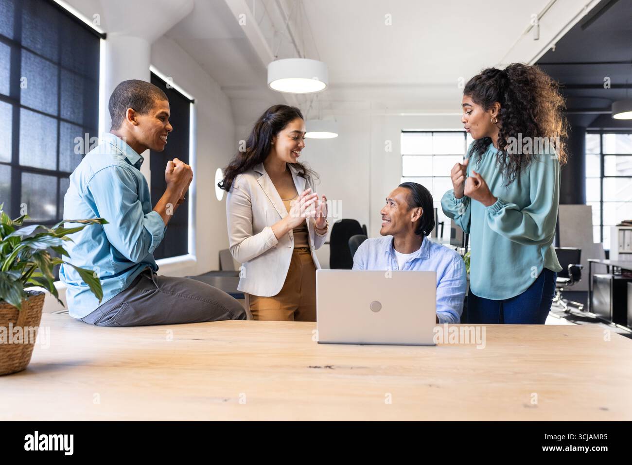 Team aziendale diversificato che collaborano intorno ai notebook in un ufficio moderno, condividendo idee Foto Stock