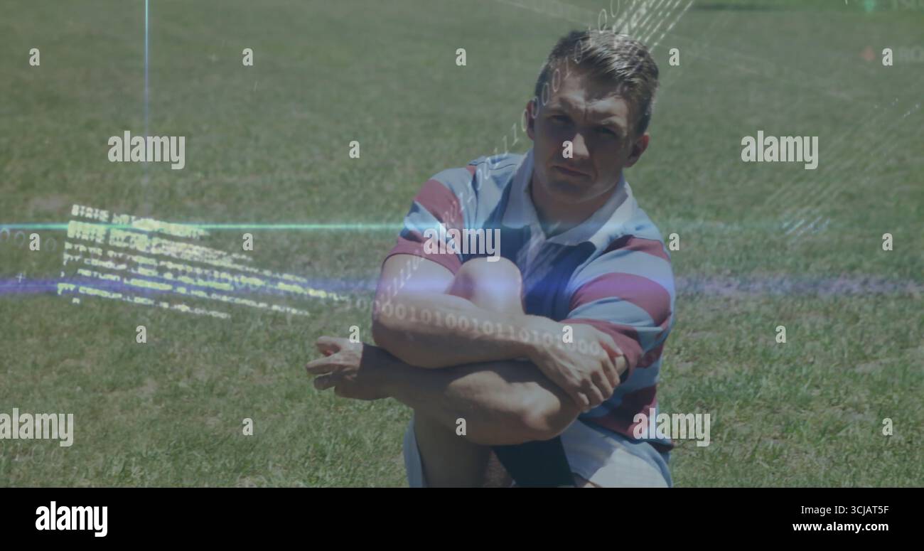 Uomo seduto che abbraccia le ginocchia a gambe incrociate sul campo d'erba, indossa camicia a righe e pantaloncini leggeri Foto Stock