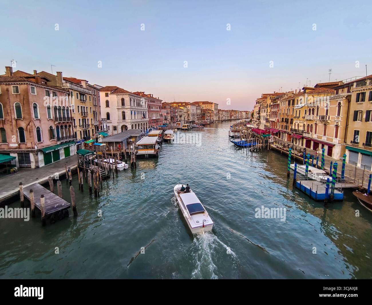 Una mattinata tranquilla su un pittoresco canale di Venezia, in Italia. L'immagine cattura le acque turchesi brillanti che riflettono le facciate logore di un edificio storico Foto Stock