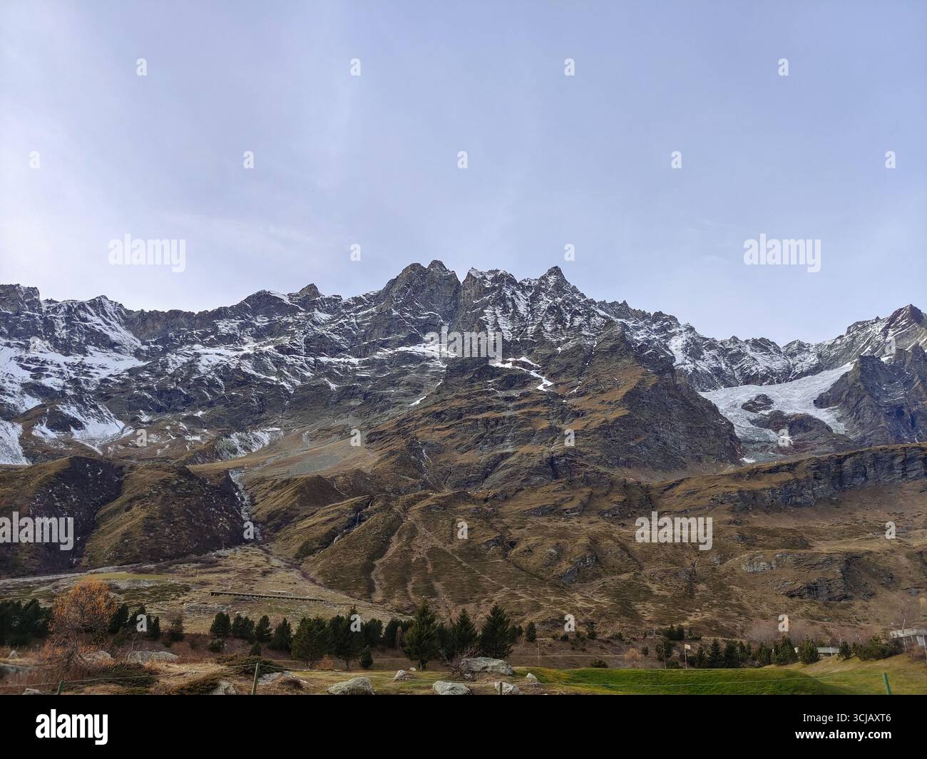 Una maestosa e aspra catena montuosa della Valle d'Aosta, in Italia, con vette frastagliate spolverate di neve fresca. L'immagine cattura l'immensa scala dell'i Foto Stock