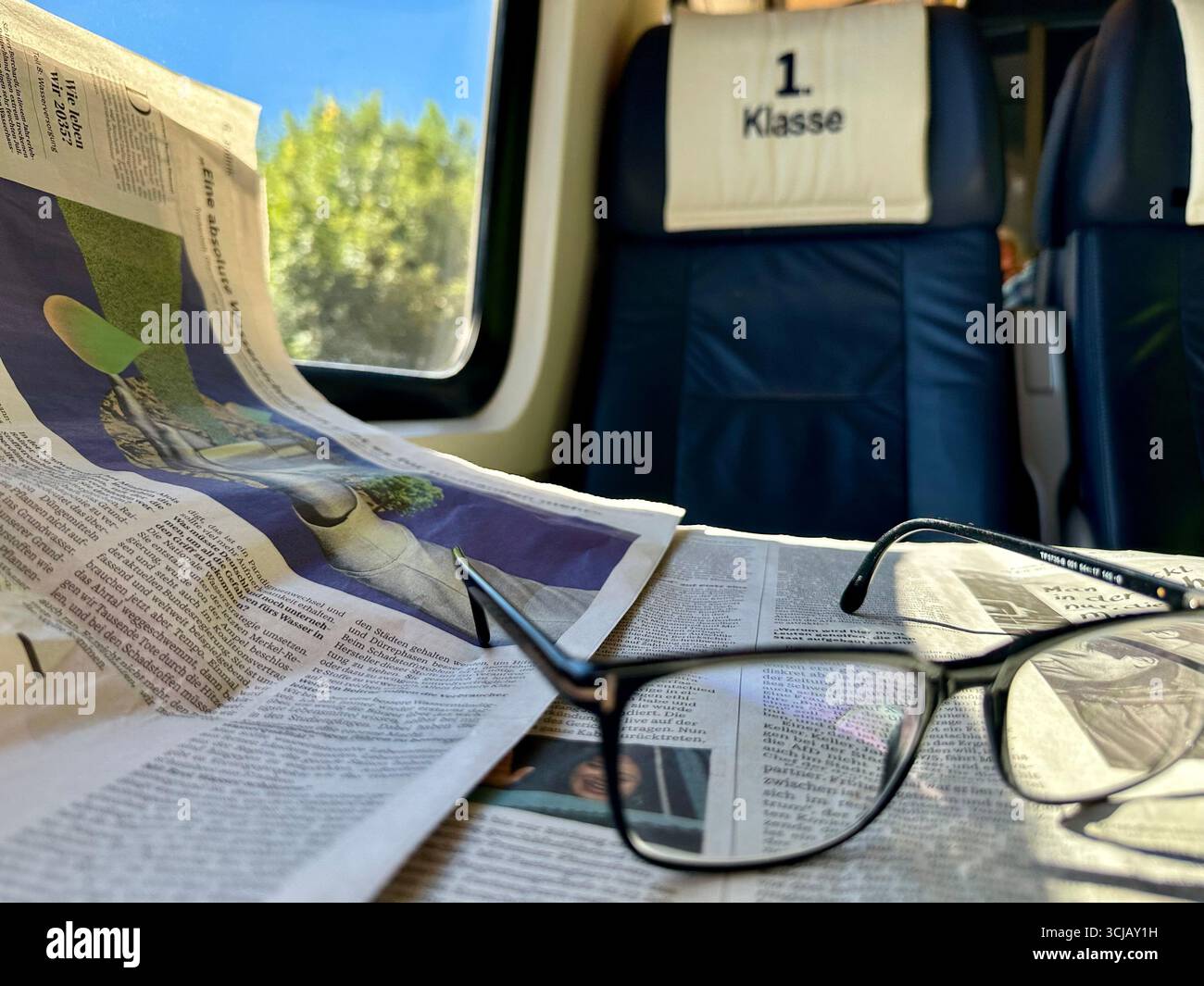 Leggere occhiali e un giornale tedesco nella sezione di prima classe di un treno regionale tedesco Foto Stock