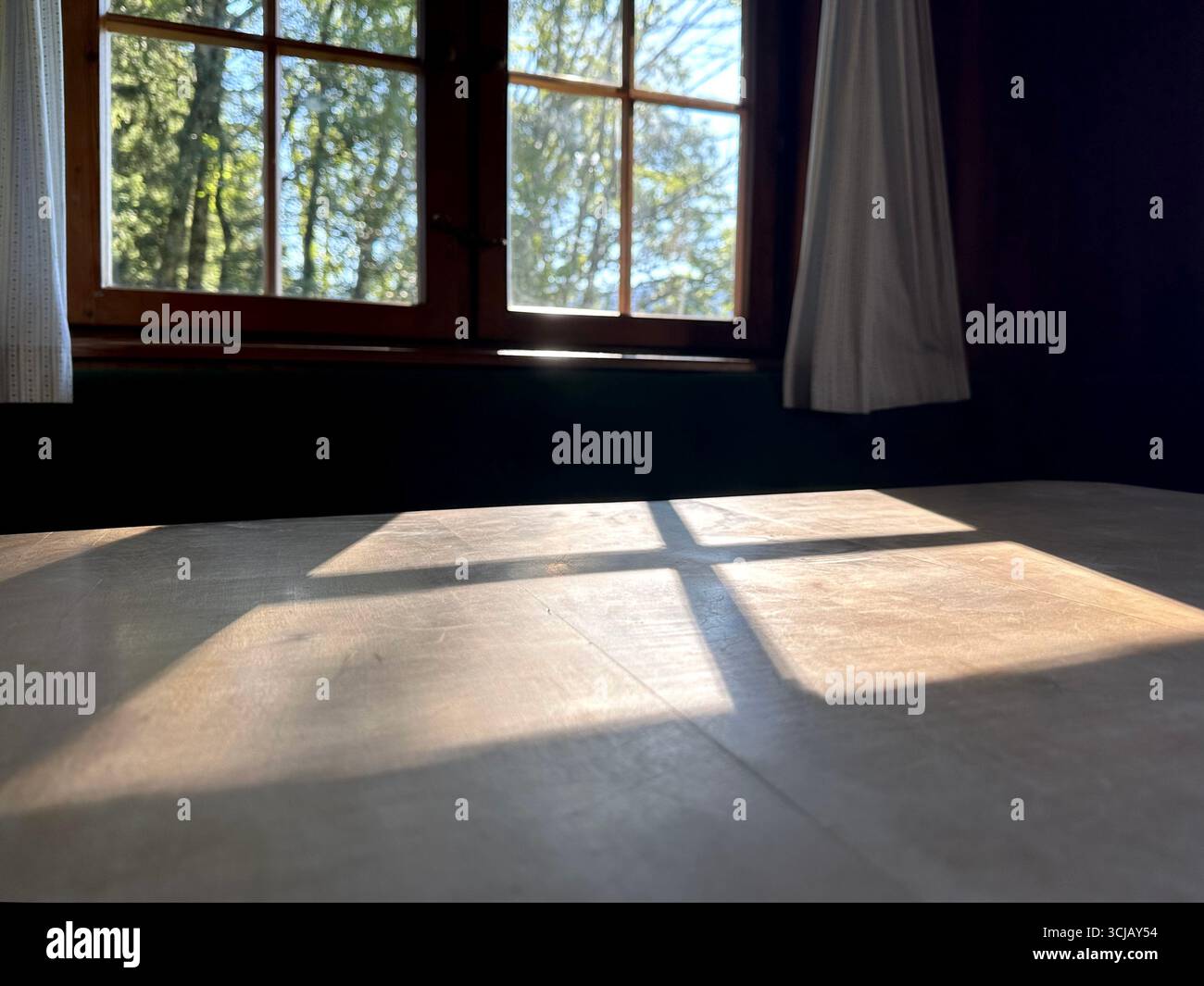 Il sole splende attraverso una tradizionale finestra a reticolo che getta un'ombra su una superficie di legno Foto Stock