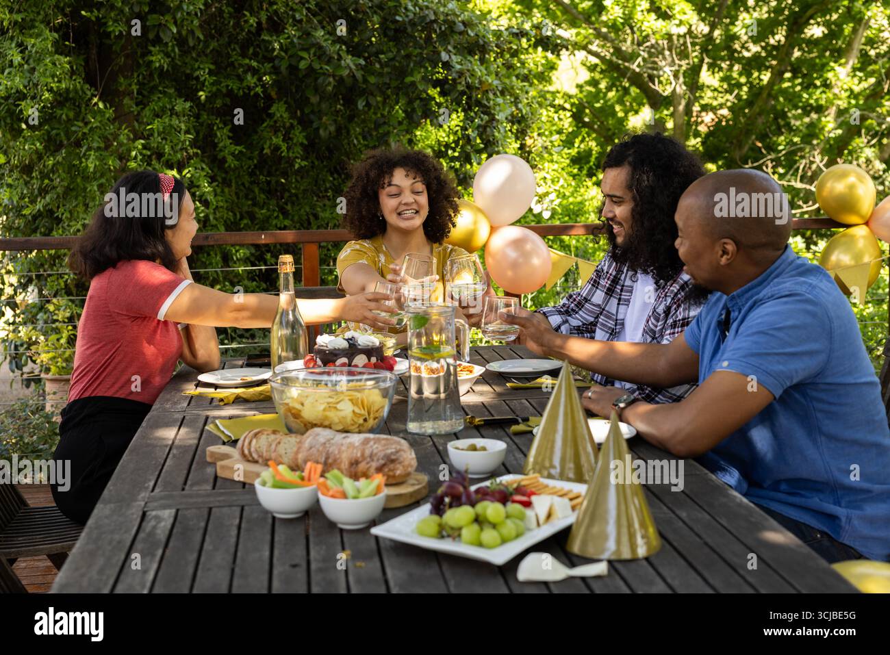 Brindate con bicchieri da vino, amici che festeggiano e condividono i pasti festivi all'aperto Foto Stock
