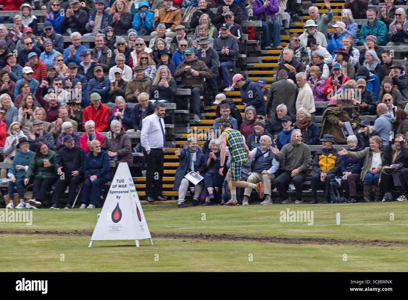 Braemar Gathering, Aberdeenshire, Scozia, Regno Unito. 6 settembre 2025. Nuvoloso a Braemar per gli Highland Games, che ospitano il re e la regina all'evento annuale. 6 settembre 2025. Nella foto: Un sostenitore della Fondazione My Name Is Dobbie, vestito con i suoi colori tartan, celebra il suo ritorno nell'arena con il pubblico apprezzante. Credito: Arch White/alamy notizie dal vivo. Foto Stock