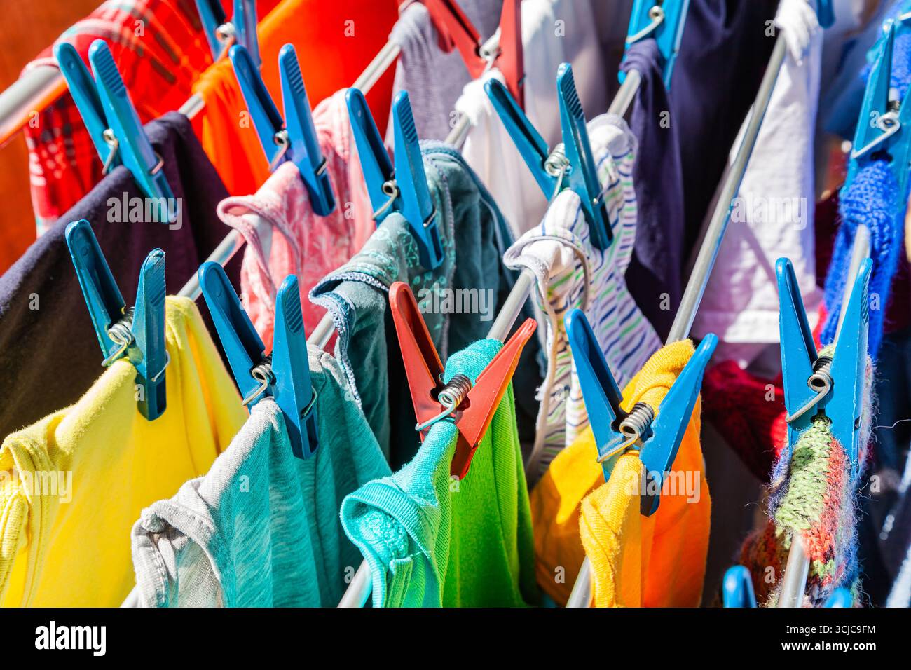Gli abiti multicolore sono attaccati ai clothespins e asciugati dopo il lavaggio, primo piano. Foto Stock