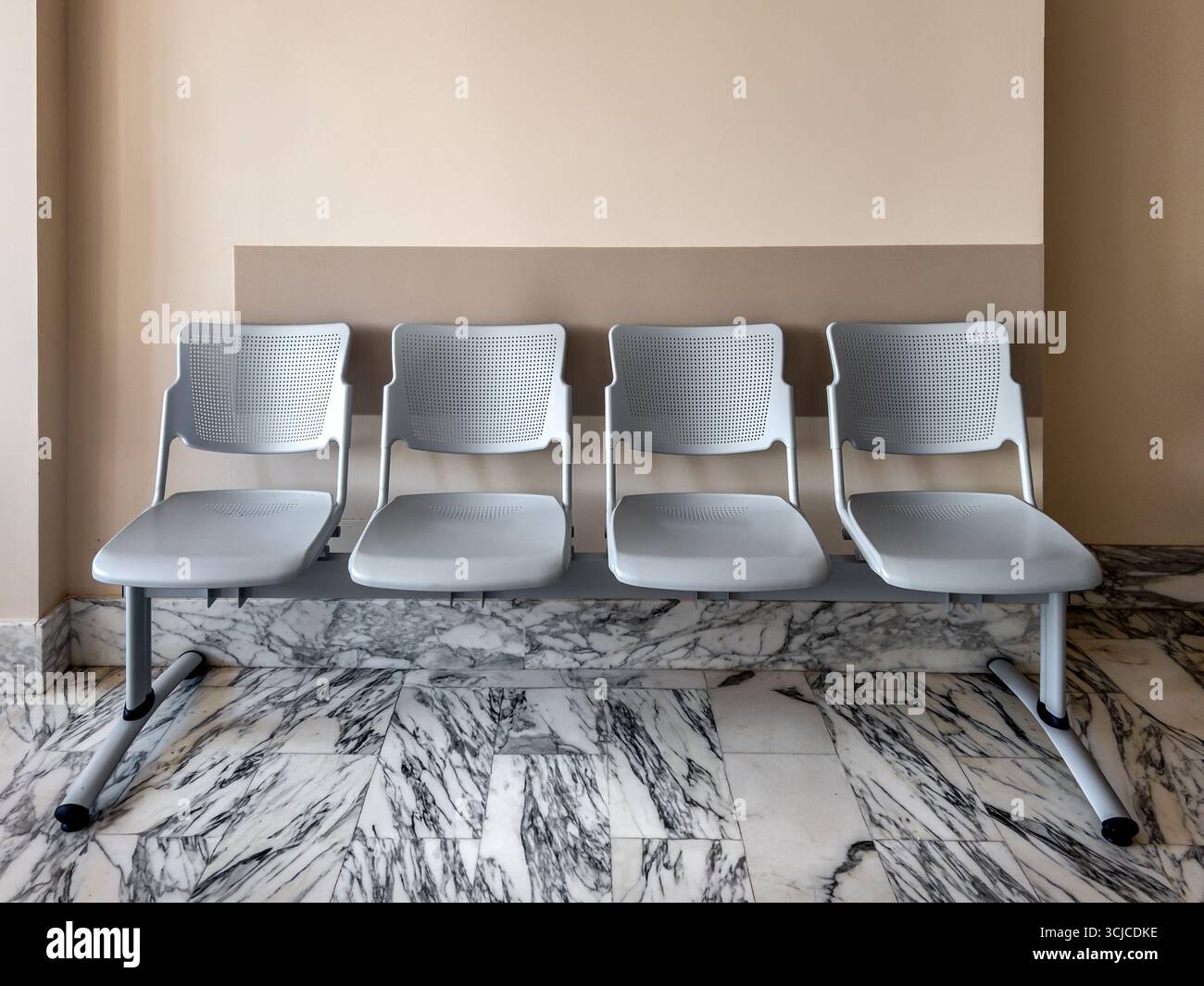 Sala d'attesa minimalista con una fila di sedie su pavimento in marmo bianco venato nero Foto Stock