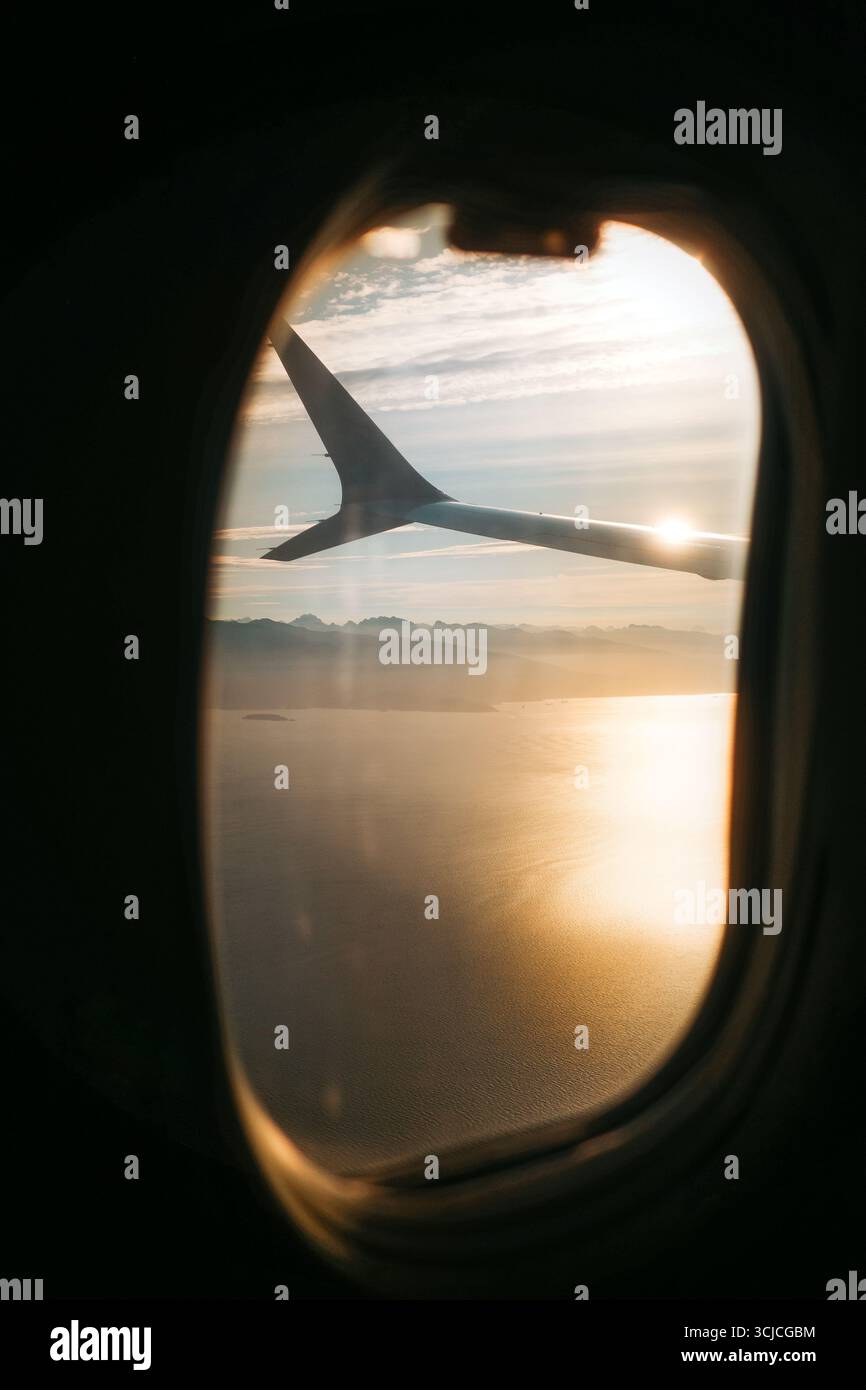 Una splendida vista dalla finestra di un aereo che mostra l'ala sullo sfondo di un tranquillo tramonto, catturando la tranquilla bellezza di volare sopra le nuvole Foto Stock