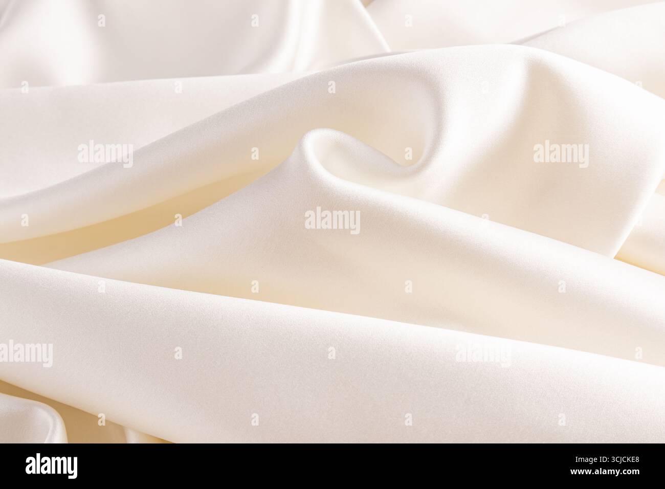 Lussuoso tessuto in raso avorio con pieghe fluide che creano una texture liscia ed elegante. Perfetto come sfondo per temi di matrimonio, progetti di moda, Foto Stock