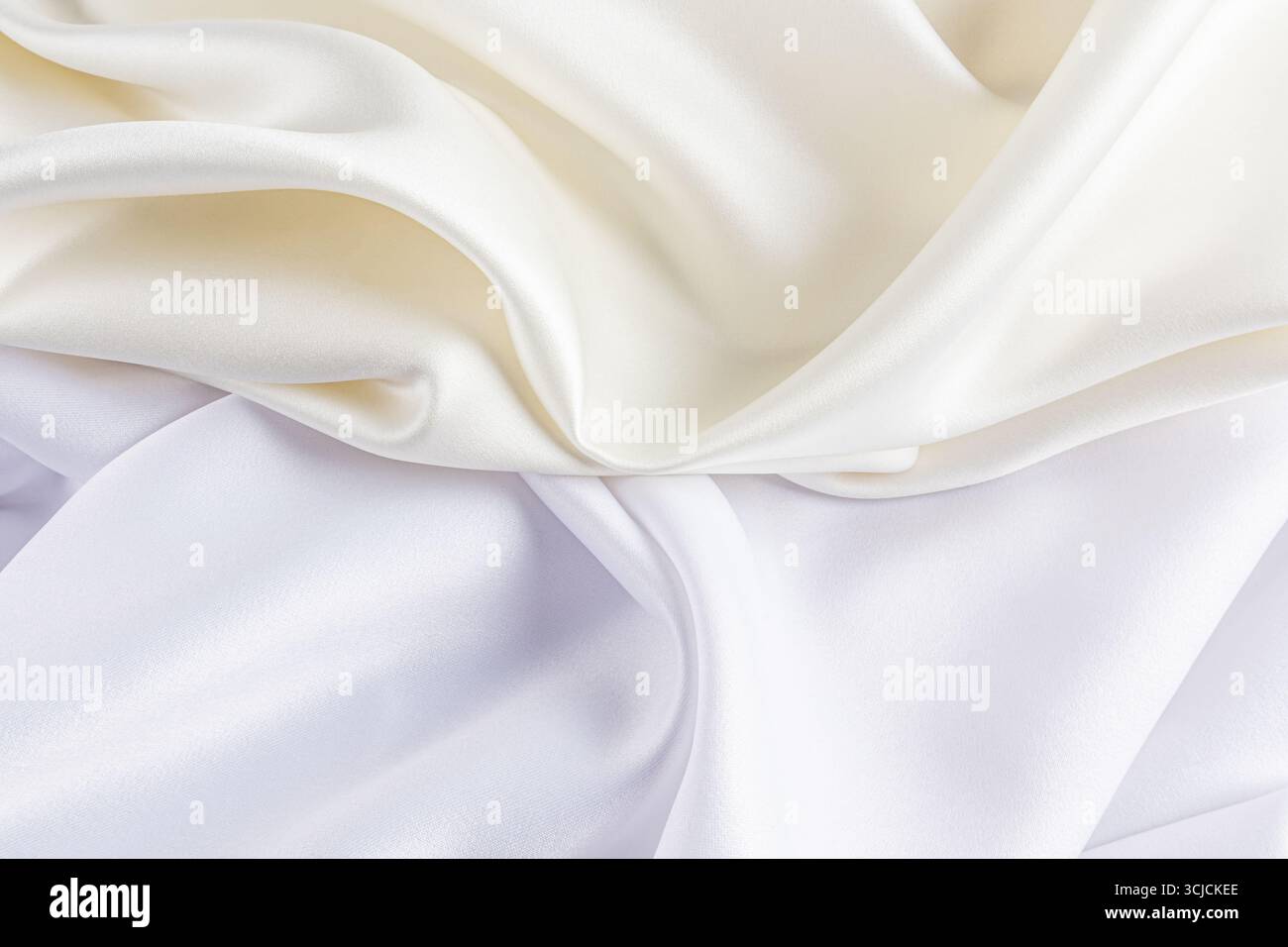 Il lussuoso tessuto in raso bianco e avorio crea uno sfondo liscio ed elegante con morbide pieghe. La texture lucida aggiunge un tocco sofisticato, perfetto per Foto Stock