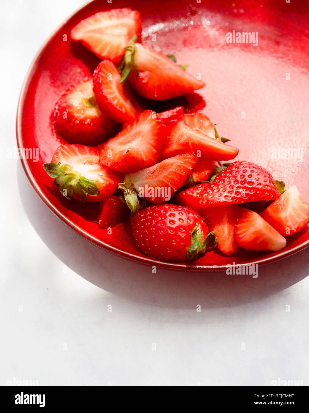 Le fragole fresche e succose sono disposte su un piatto rosso vivace, creando un contrasto sorprendente. I colori vivaci e i prodotti freschi lo rendono un'allettante Foto Stock
