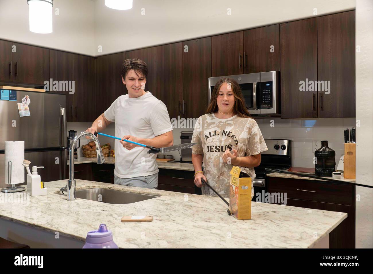 Un gruppo di giovani adulti che si diverte a cucinare insieme in una cucina moderna Foto Stock