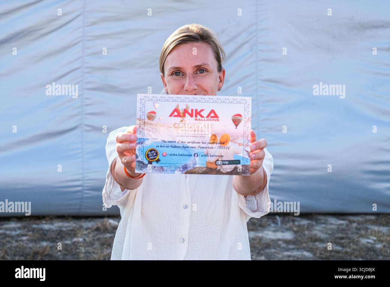 pamukkale, Turkiye, 08.07.2025 donna in possesso di certificato per volo in mongolfiera su Pamukkale, Turchia. Esperienza di viaggio e concetto turistico. Foto Stock